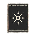 A black woven throw blanket with a central white SUN NINA sunburst emblem, white text at the top and bottom, and multicolored fringed edges, shown flat against a white background.